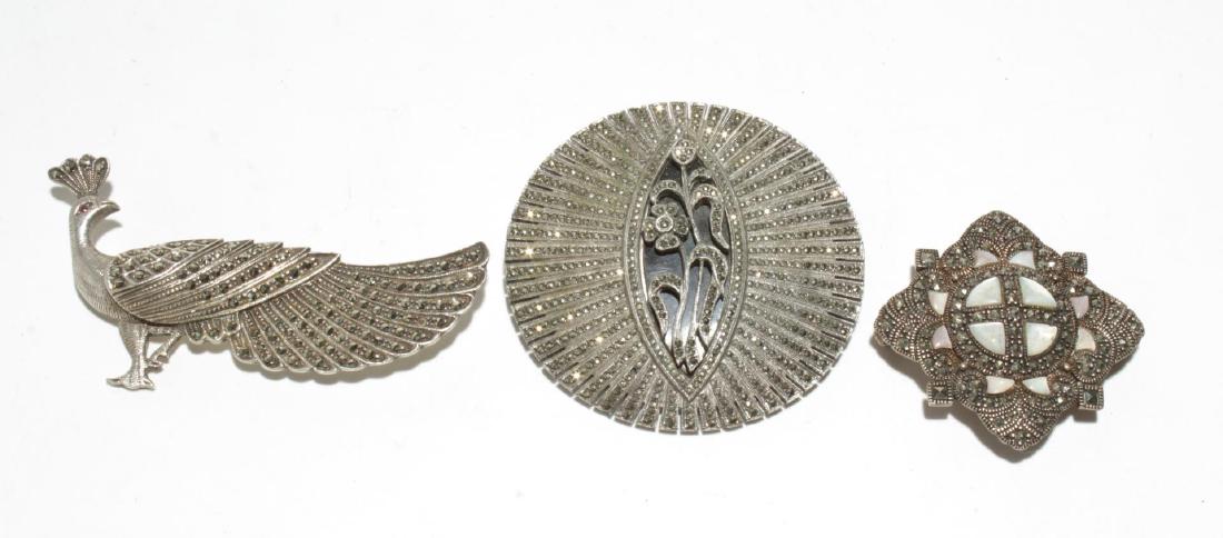 Silver & Marcasite Woman's Brooches, 3 Pins: Vintage sterling silver & marcasite woman's brooches, one further with mother-of-pearl and marked "Joielle," all three stamped either "925" or "Sterling." Largest: 2.25" diameter. Approx. 2.2 ozt.