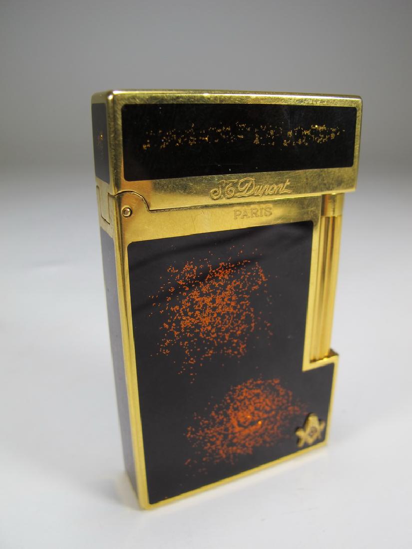 S.T. Dupont Masonic lacquer gold dust lighter: S.T. Dupont Masonic lacquer gold dust lighter with applied gold Freemasonry symbol on the low right corner. 2 1/2" H x 1 1/2" W x 7/16" D. Shipping in USA or International please contact both UPS stor