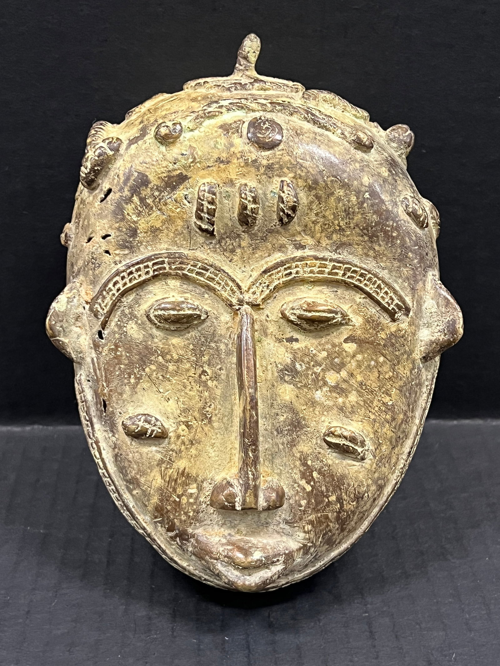 Bronze Baule Mask: African Tribal Art Bronze Baule Mask. The dimension is 7.5 inches high x 5.5 inches wide. Please be aware that some of the items are vintage, secondhand, old ages, antiques and may have a defects or s