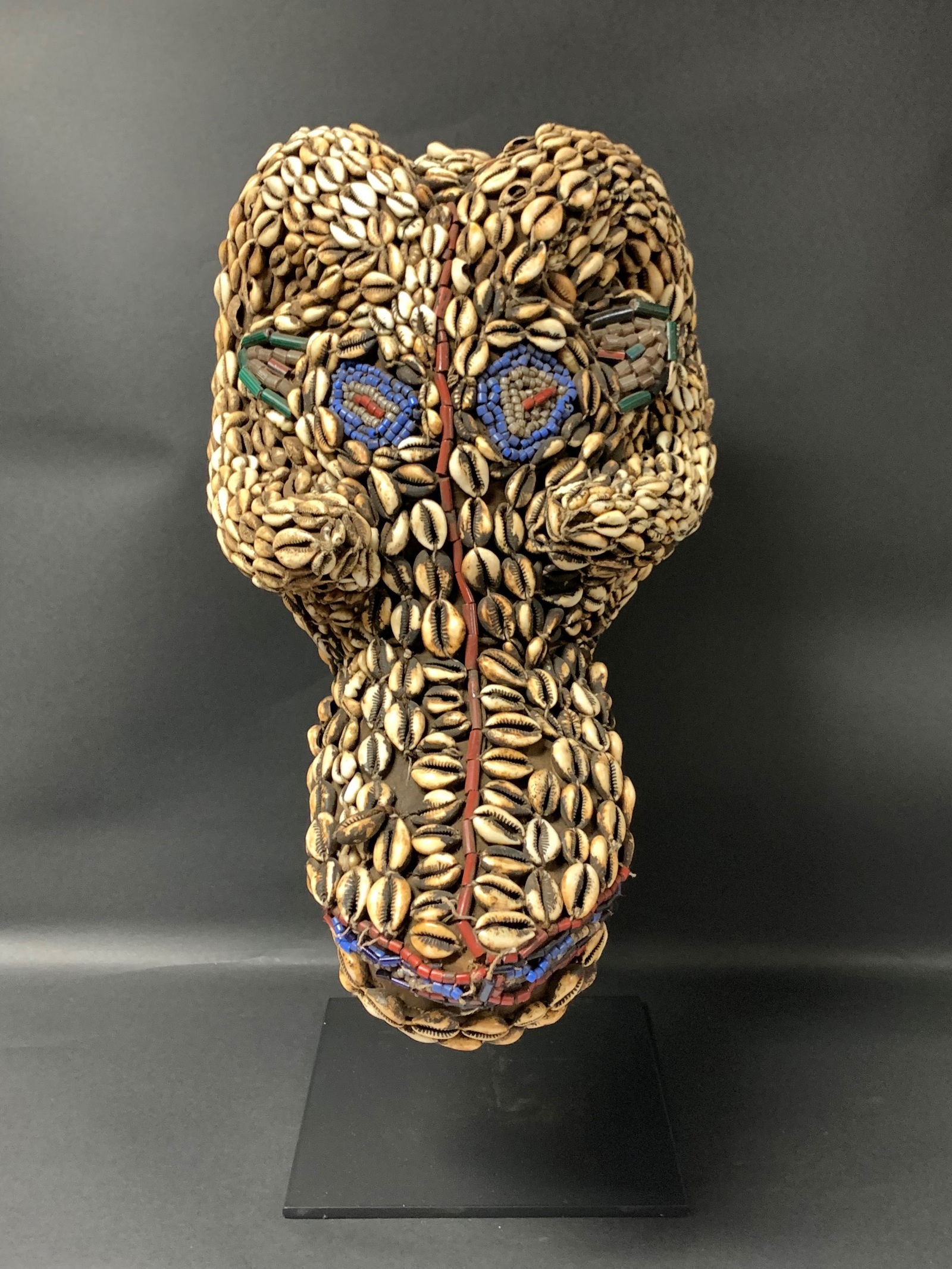 Bamana Cowrie Shell Mask with Display Stand: African Tribal Art Bamana Cowrie Shell Mask with Display Stand. The dimension is 17 inches high x 7 inches wide. Please be aware that some of the items are vintage, secondhand, old ages, antiques and