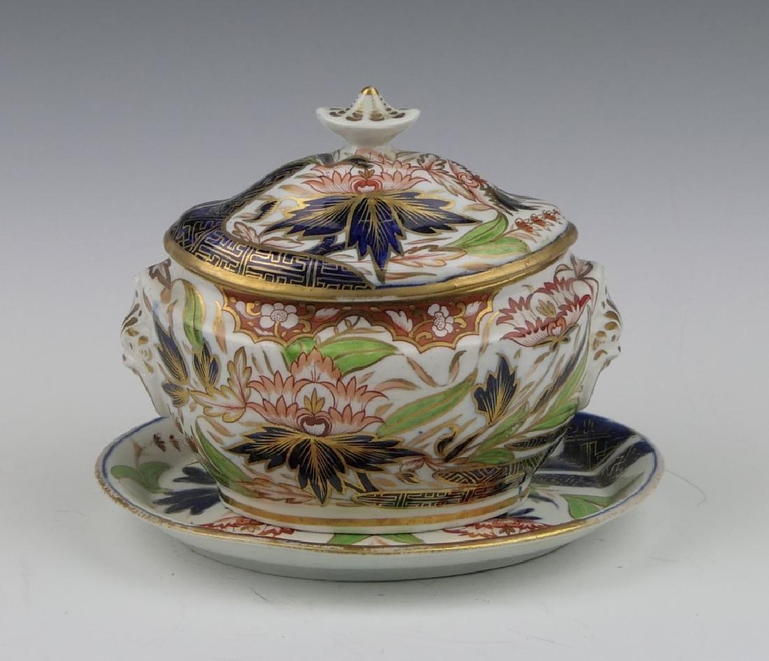 ANTIQUE ENGLISH JAPONISM LOTUS COVERED BOWL: Antique English hand painted covered sauce bowl with under plate having a hand painted lotus blossom design with leaves utilizing the Imari iron red with cobalt blue palette accented with green leaves