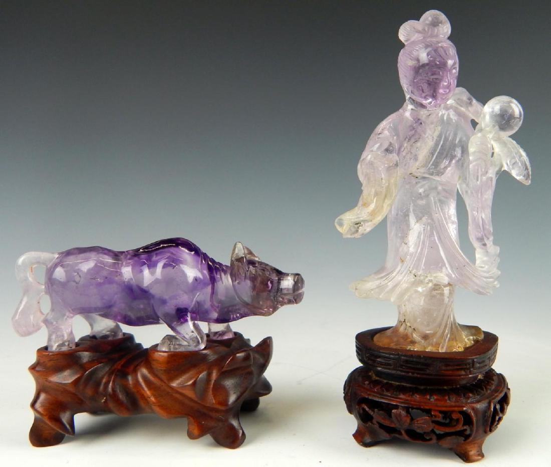 2 CHINESE CARVED AMETHYST QUARTZ STONE CARVINGS: A lot of 2 Chinese carved amethyst purple and clear quartz sculptures with fitted wooden bases to include Quan Yin with peaches and a zodiac ox. Tallest measures approx. 4 1/4" height (10.8cm) includi
