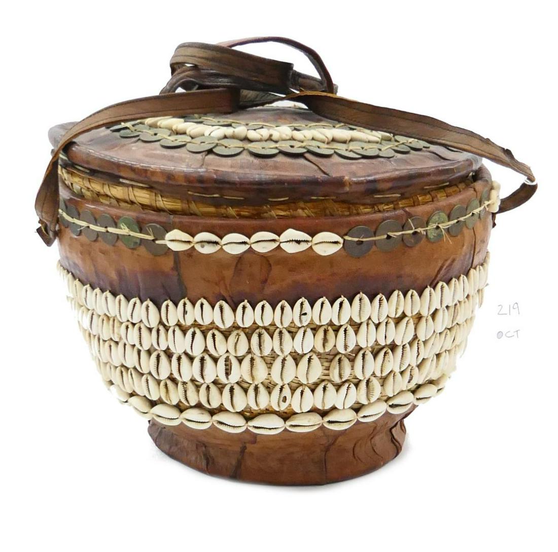 VINTAGE AFRICAN NIGERIA LEATHER BOUND WEDDING BOX: A stunning vintage Nigerian wedding box crafted of woven wicker wrapped in leather. Adorned throughout with cowry shells and 1959 Queen Elizabeth II Republic of Nigeria bronze pennies. Measures approx