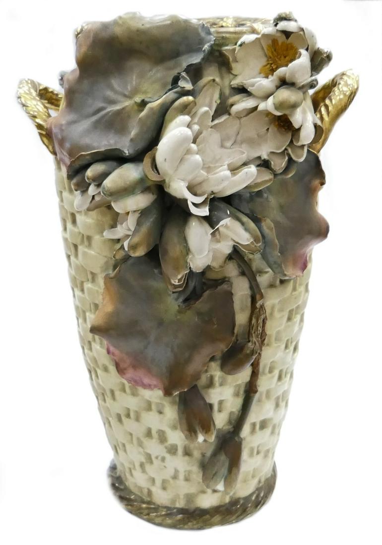 LARGE ART NOUVEAU AMPHORA POTTERY BASKET VASE: A large Art Nouveau Riessner, Stellmacher & Kessel Amphora Austria Turn-Teplitz Bohemia pottery vase having a woven wicker design with chrysanthemum blooms and leaves; completed with golden handles. I