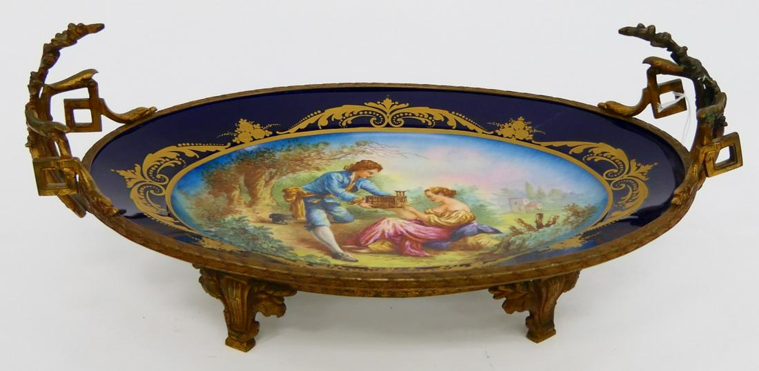 CHARLES MARTIN LIMOGES DORE BRONZE MOUNTED PLATTER: Antique Charles Martin Limoges French hand painted oval porcelain platter depicting a courting couple with bird and bird cage signed "J PErrot". Oval dish is mounted in dore gilt bronze mount with flr