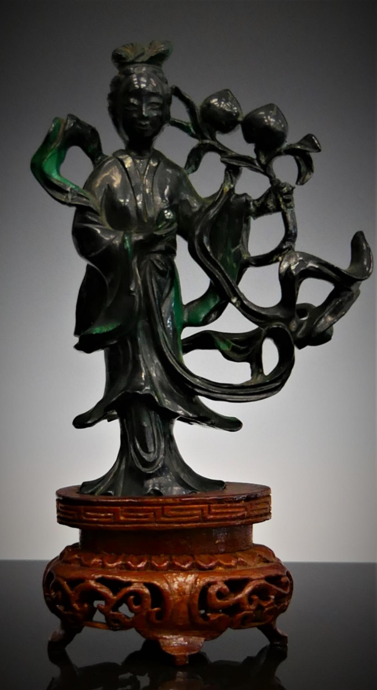 CHINESE CARVED MALACHITE STONE GUANYIN SCULPTURE: A Chinese hand carved malachite stone sculpture depicing Quan Yin holding peaches on stalks. Includes fitted wooden base. Measures approx. 5 3/4" height (14.6cm) overall including base. Total stone we