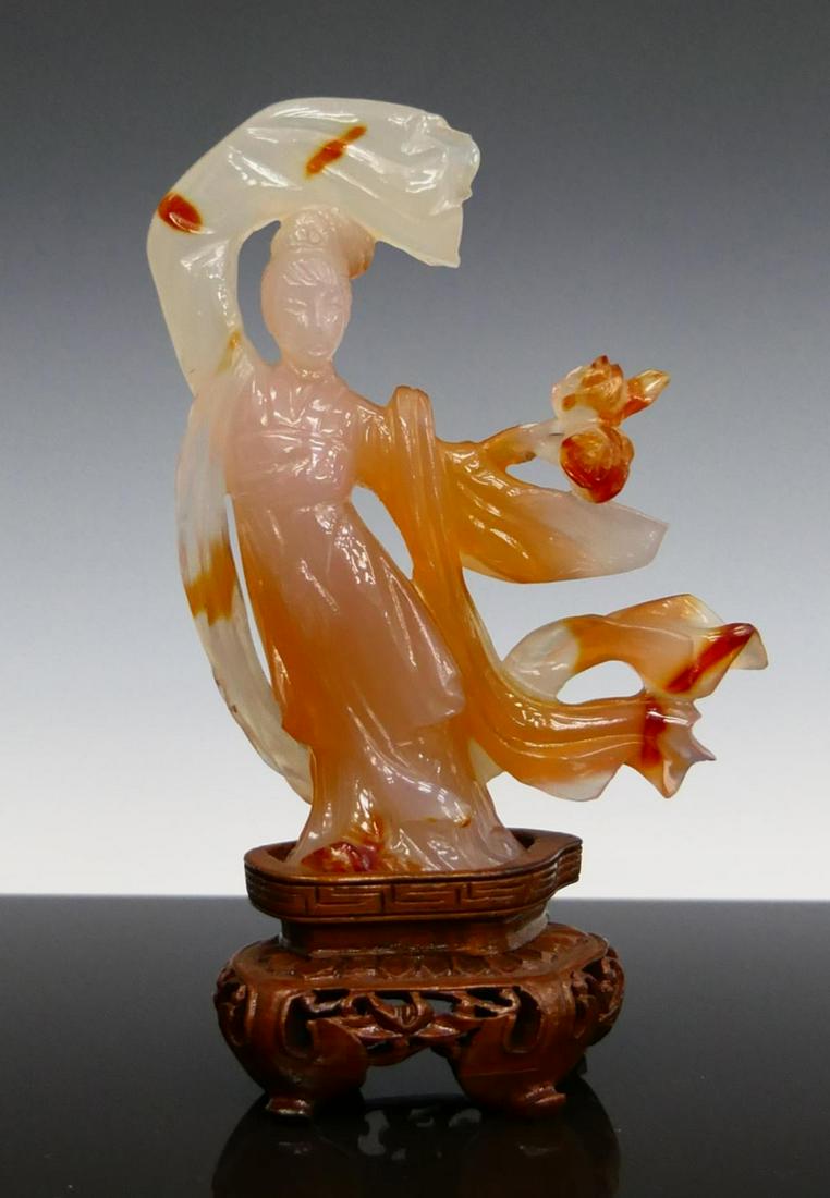 CHINESE CARNELIAN AGATE QUAN YIN SCULPTURE: Chinese carved carnelian agate sculpture depicting Guan Yin. Includes fitted wooden display base. Measures approx. 6" height (15.2cm) overall including stand. Total stone weight approx. 130.3 grams NO