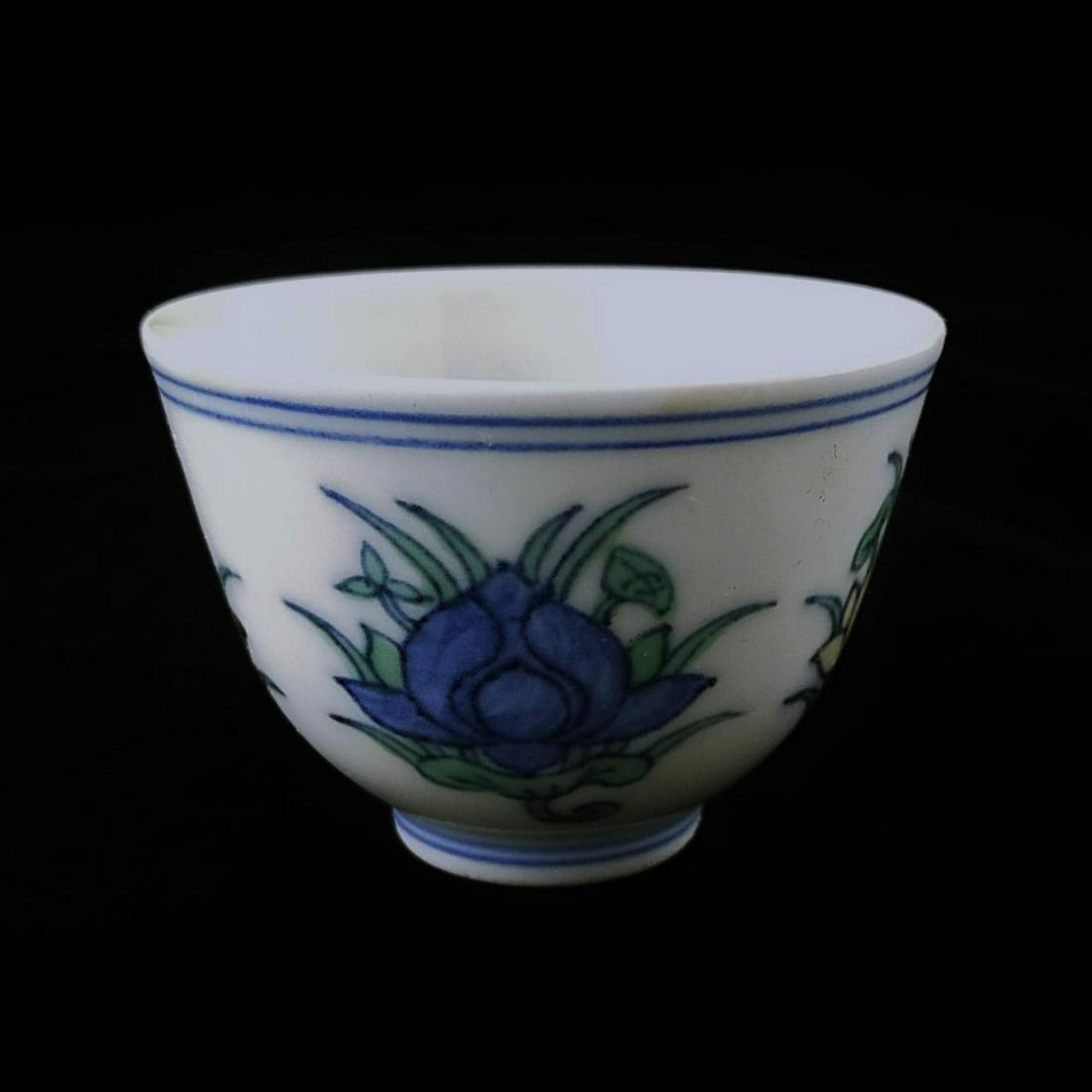 CHINESE DUCAI PORCELAIN LOTUS BLOSSOM WINE CUP: Chinese hand painted Ducai porcelain wine cup depicting lotus blossoms. Bottom holds blue six character calligraphy Ming Dynasty Chenghua reign mark. Measures approx. 1 5/8" height x 2 1/8" diameter (