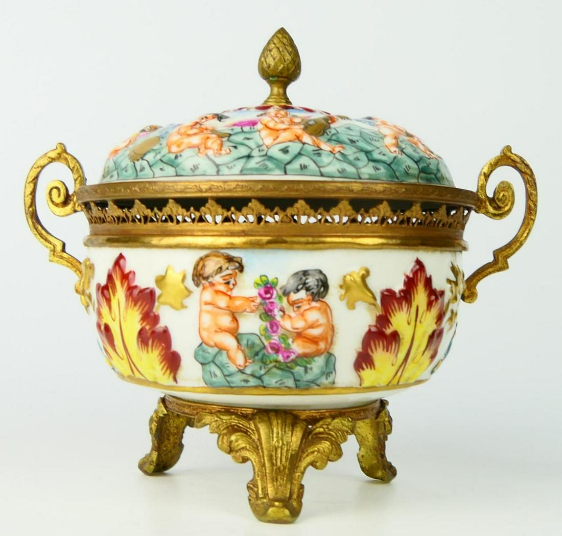 FRENCH DECORATED CAPODIAMONTE FOOTED BOWL: Measures 7" wide, handle to handle, and stands 6" tall to finial, cherub design