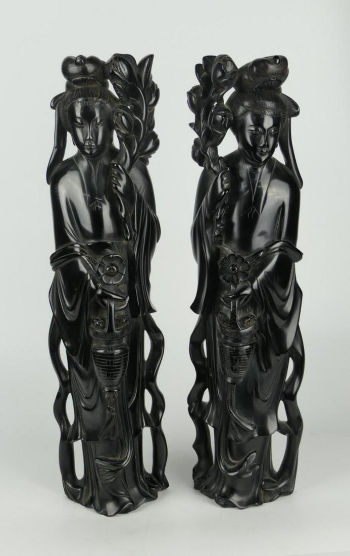 Pr LARGE CHINESE FAUX BLACK ONYX MAIDENS SCULPTURE: A pair of Chinese carved resin faux black onyx or ebony large sculptures depicting maidens holding flower baskets and lotus stalks in flowing garb. Each measures approx. 19 1/2" height x 5 1/2" width