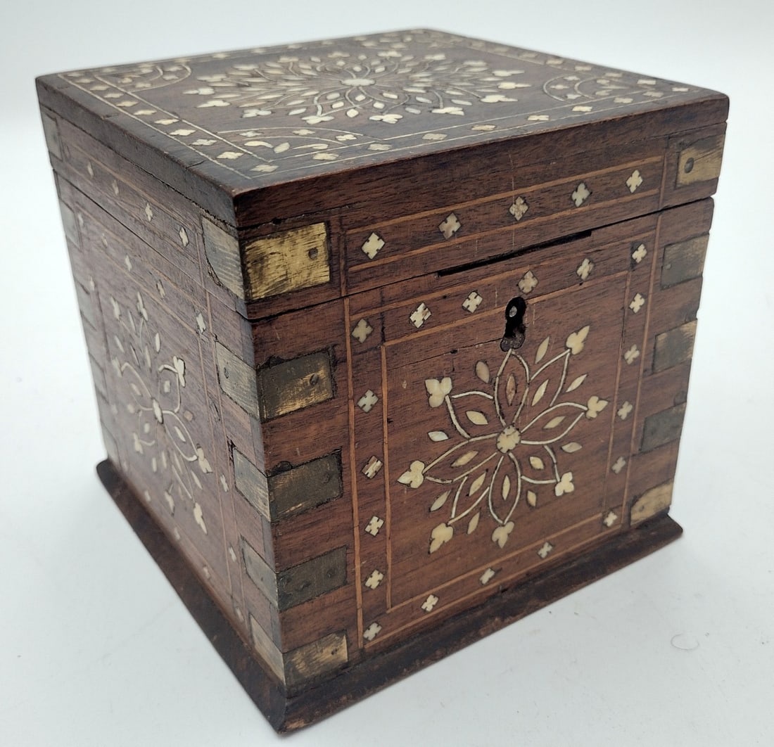 Antique English Bone Inlaid Wooden Tea Caddy: Antique English wooden tea caddy having an ornate inlaid bone floral design. Further accented with brass inlay. No apparent hallmarks. Measures approx. 5 3/4" height x 5 3/4" width x 5 3/4" depth.