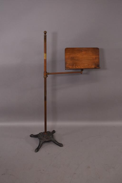 ANTIQUE IRON BASE MUSIC STAND: IRON BASE HAS FACES AS DECORATION -- BRASS POLE WITH ADJUSTABLE HEIGHT -- OAK STAND -- 49" H