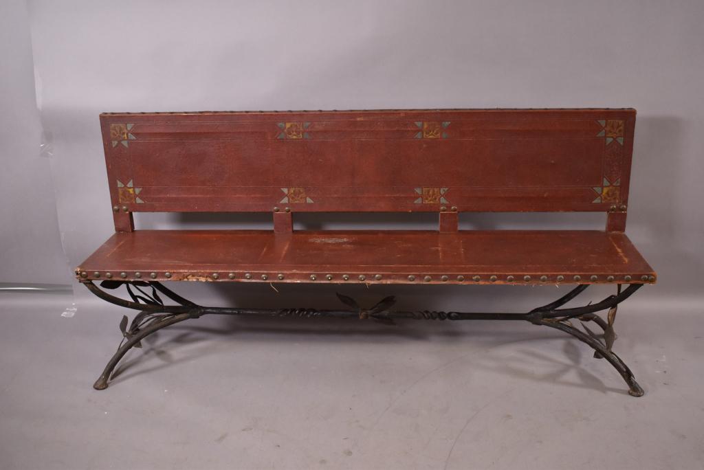 1920'S IRON BASE SPANISH STYLE BENCH: HAND PAINTED LEATHER SEAT AND BACK -- MISSING SOME TACKS ON FRONT OF LEATHER -- LEATHER IS AS IS -- ONE LEAF BROKEN ON FRONT IRON -- 72" x 17 1/2" x 32"