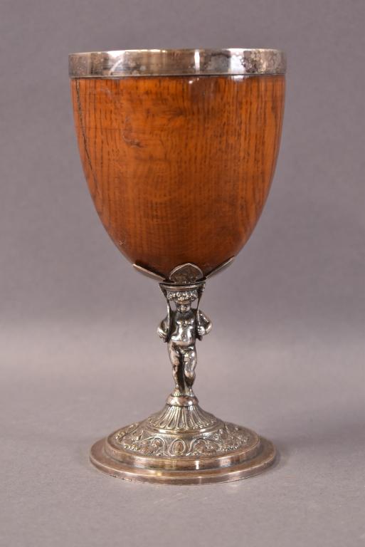 ENGLISH SILVER PLATE AND WOODEN GOBLET: CHERUB FIGURE STEM, MARKED H.B 1731 ON BASE. ONE SMALL CRACK TO WOOD. 6 3/4" H