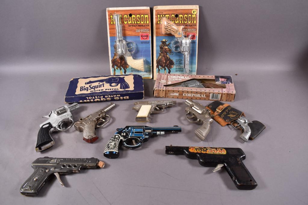 LOT OF 12 CAP GUNS, SQUIRT GUNS, & CORK GUNS: 8 ARE CAP GUNS INCL.: KIT CARSON KILGORE IN ORIGINAL PACKAGES. 1 SQUIRT GUN & 3 TIN GUNS