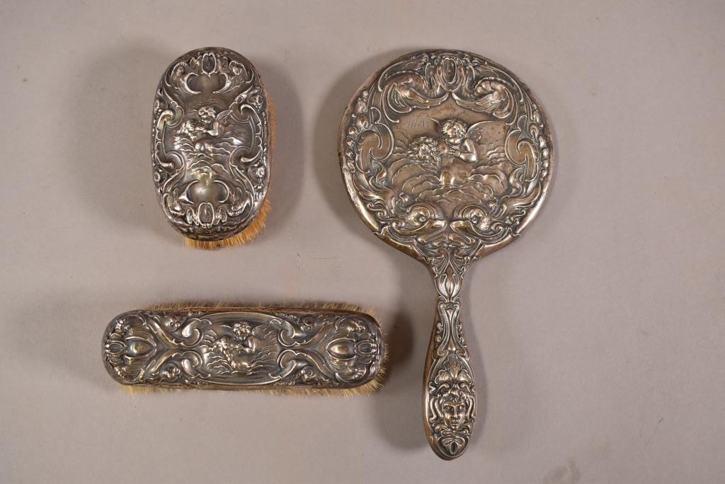 3 PIECE STERLING CHERUB DRESSER SET: STERLING CHERUB DECORATED SET. 2 BRUSHES AND HAND MIRROR. MARKED STERLING. GOOD OVERALL CONDITION. 4 1/2" - 9" L
