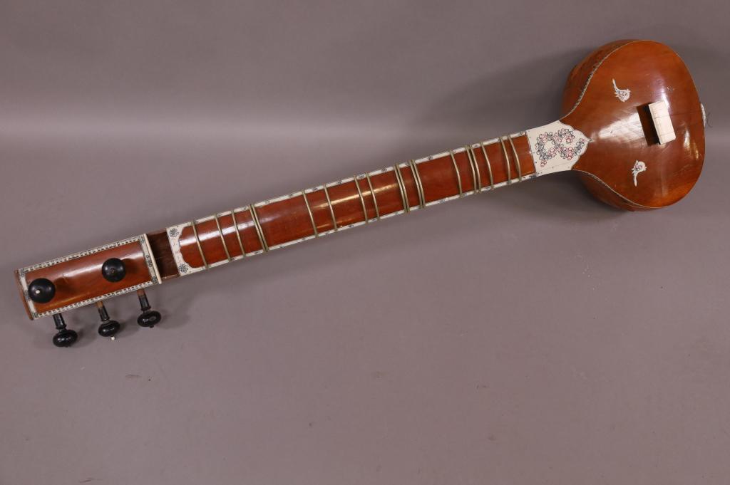 SITAR: INLAID SITAR, MISSING 1 PANEL BY BRIDGE AND TUNING KNOBS. HAS DAMAGE IN TOP. 46" LONG. THIS ITEM EXEEDS SIZE LIMITATIONS FOR IN HOUSE SHIPPING.