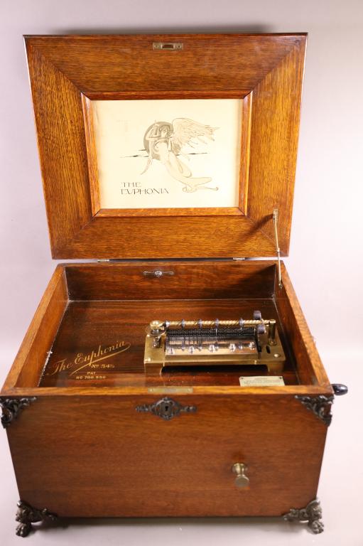 EUPHONIA OAK COIN OP MUSIC BOX: THE EUPHONIA 54 1/2. PAT. 700.550. WITH (7) 15 3/4" RECORD. LION DECORATED, METAL FOOTED CASE. WITH CRANK. COIN OP 5 CENT. WORKING CONDITION. 20 1/2" W x 18" D x 13" H. THIS ITEM EXCEEDS SIZE LIMITATI