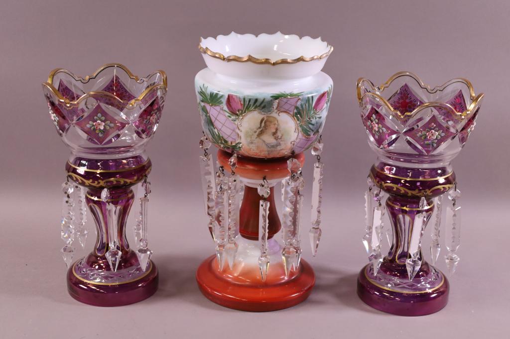 LOT OF 3 MANTLE LUSTERS: PR. OF BOHEMIAN AMETHYST & CLEAR LUSTERS W/ FLORAL DECORATION & SINGLE VICTORIAN LUSTER W/ LADY DECORATION (HAS SOME MINOR PAINT LOSS). PAIR IS 10 1/4" TALL & SINGLE IS 12" TALL