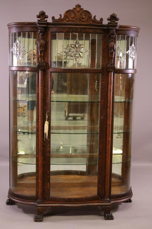 1900'S AM. OAK LEADED GLASS CHINA CABINET: LEADED GLASS TOP, BOW FRONT AND SIDE CHINA CABINET, MIRRORED BACK. CLAW FOOT. MINOR FINISH WEAR. 49" W x 20" D x 73" H. THIS ITEM EXCEEDS SIZE LIMITATIONS FOR IN HOUSE SHIPPING.