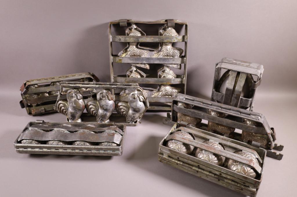 SEVEN CHOCOLATE MOLDS: EASTER EGGS, SHEEP, CHICKENS. MINOR WEAR TO SURFACE.