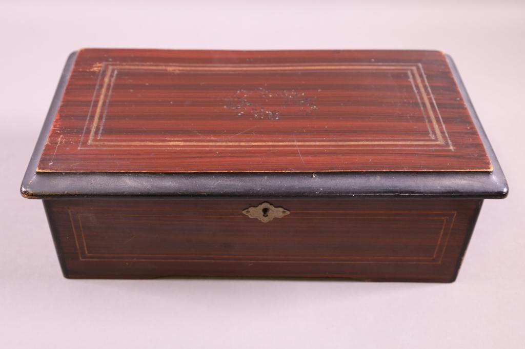 GERMAN CYLINDER ROLL PLAYER: SINGLE COMB, NO BROKEN TEETH. SIX SONG PLAYER. WORKING CONDITION. FINISH WEAR TO CASE. 12" W x 5" H.