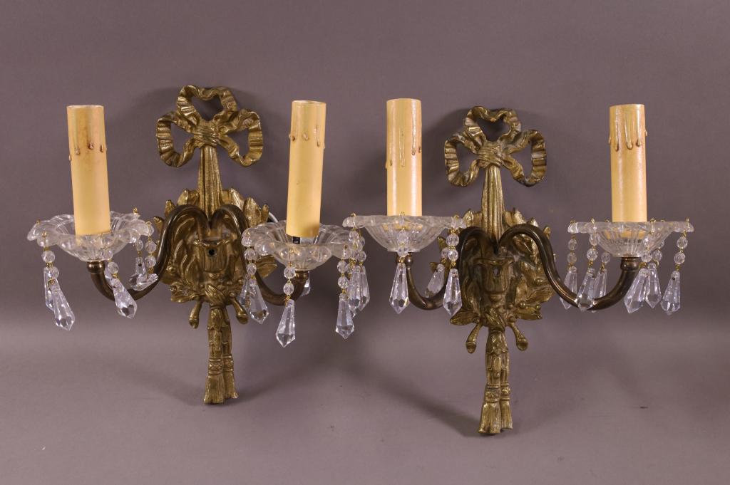 PAIR OF CAST METAL AND GLASS WALL SCONCES: RIBBON BACK DECORATION. CHIP TO ONE CUP. SOME MINOR CHIPS TO PRISMS. 10" H