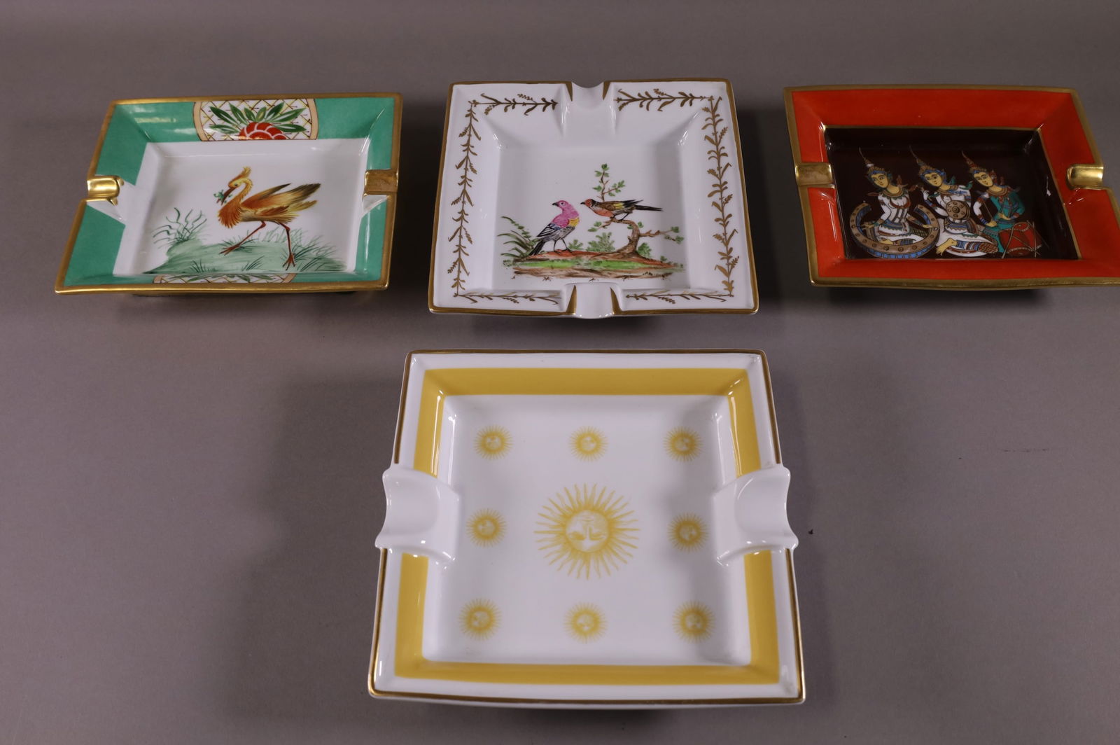 FOUR PORCELAIN ASHTRAYS: 2 HERMES (1 HAS DAMAGE), LIMOGES RAYNAUD, & UNMARKED TRAY. MINOR WEAR TO PAINT. 7 1/2" W