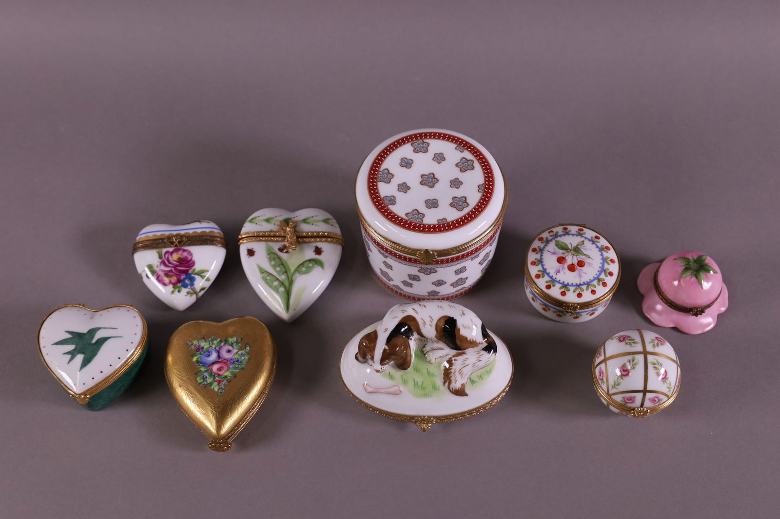 LOT OF 9 LIMOGES PORCELAIN PILL BOXES.: INCLUDING SPANIEL FORM MADE FOR TIFFANY & CO & 1 MADE FOR VAN CLEEF & ARPELS. RANGE IN WIDTH FROM 1 1/4" TO 3 1/2"