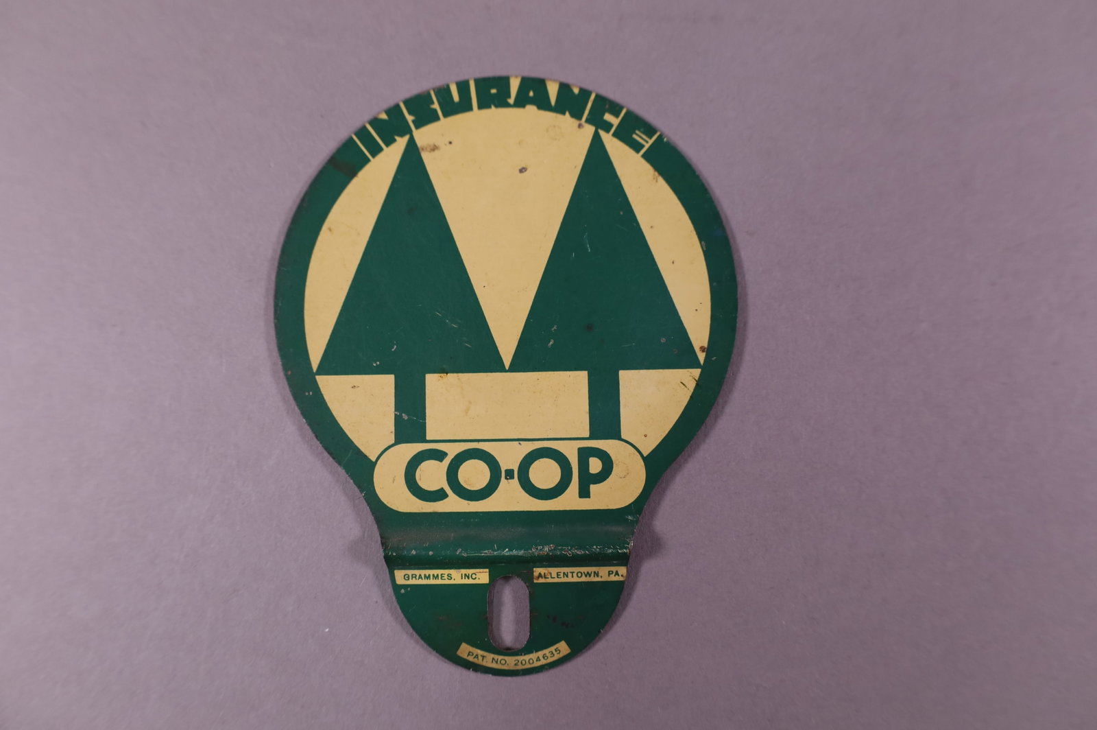 CO-OP INSURANCE TIN LICENSE PLATE TOPPER: CO-OP INSURANCE TIN LICENSE PLATE TOPPER. LIGHT SURFACE SCRATCHES. 3 1/2" DIAM,