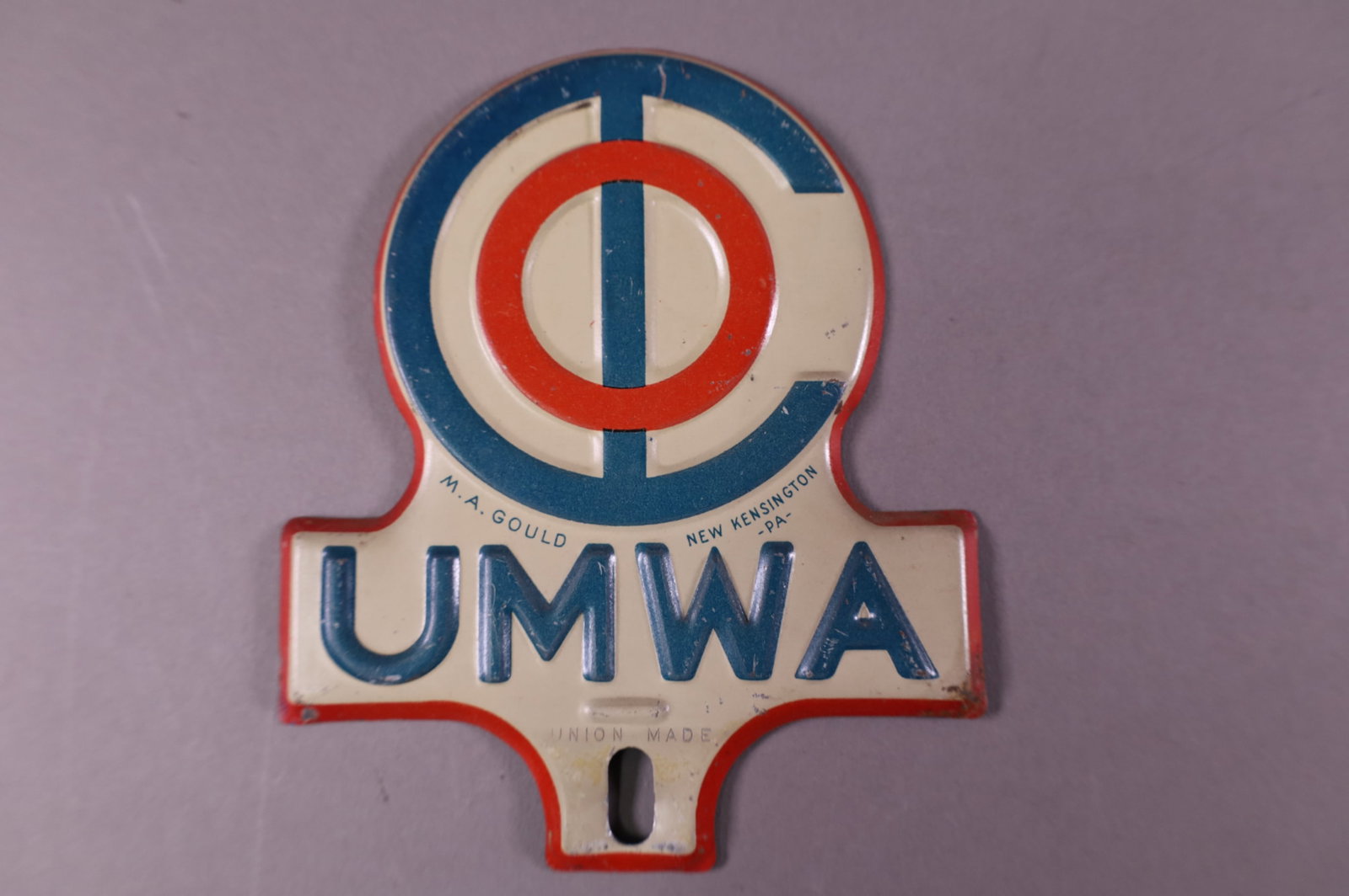 UNMA TIN LICENSE PLATE TOPPER: UNMA TIN LICENSE PLATE TOPPER. LIGHT SURFACE SCRATCHES. 4 1/4" W x 5" H