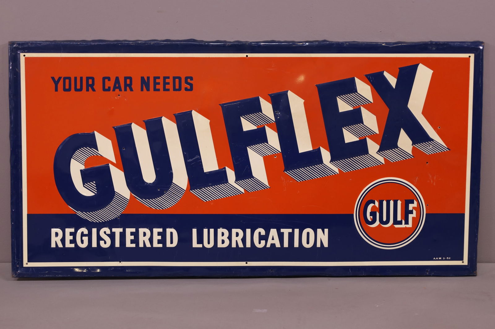 Gulflex w/Logo Metal Sign (TAC): rated 7.25, 24"x48", the SST embossed sign has good color and shine, has wear, minor creases & 12 extra nail holes in the field, marked A.A.W., dated 1952. TAC #044189