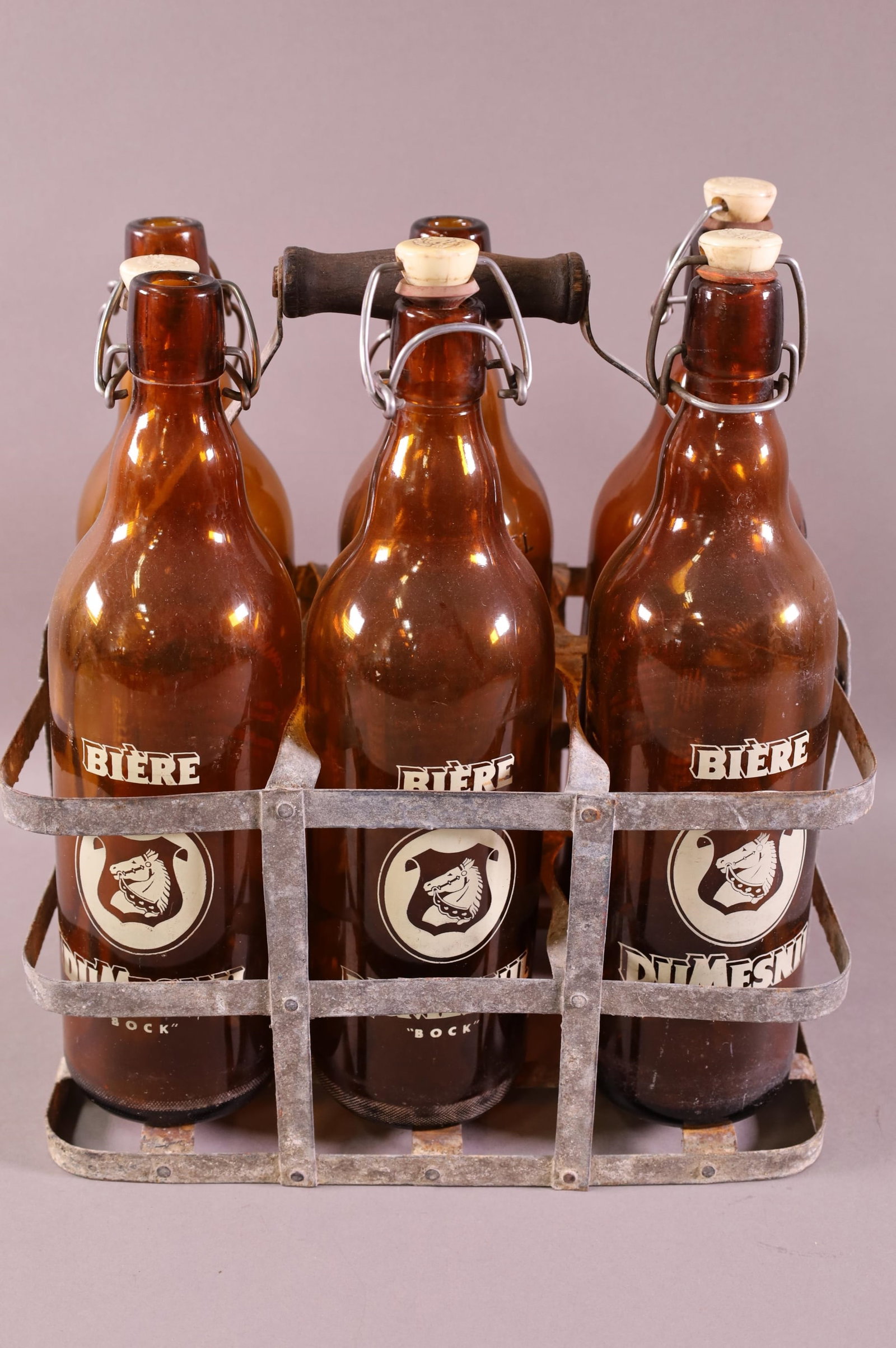 SIX PACK OF FOREIGN BEER BOTTLES IN CARRIER: "BIERE" BOCK BEER IN METAL RACK.