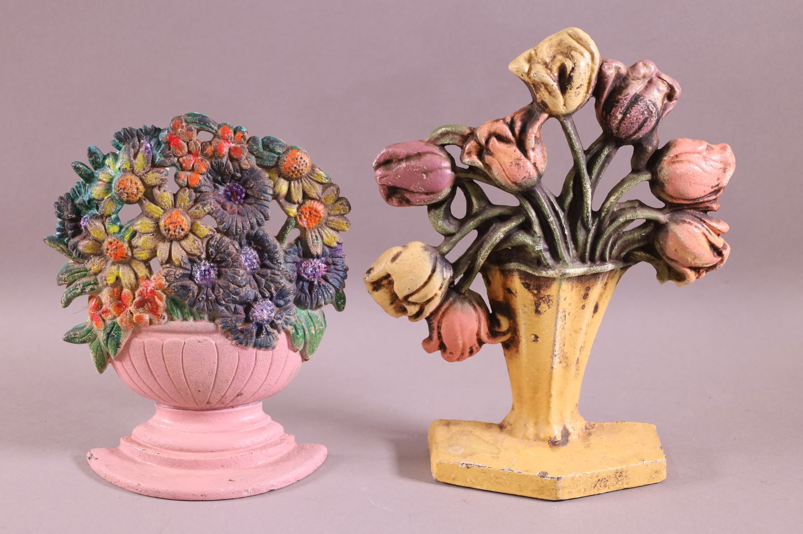 TWO CAST IRON FLOWER BASKET DOORSTOPS: TWO CAST IRON FLOWER BASKET, PAINT LOSS. 7 1/2" & 9" H