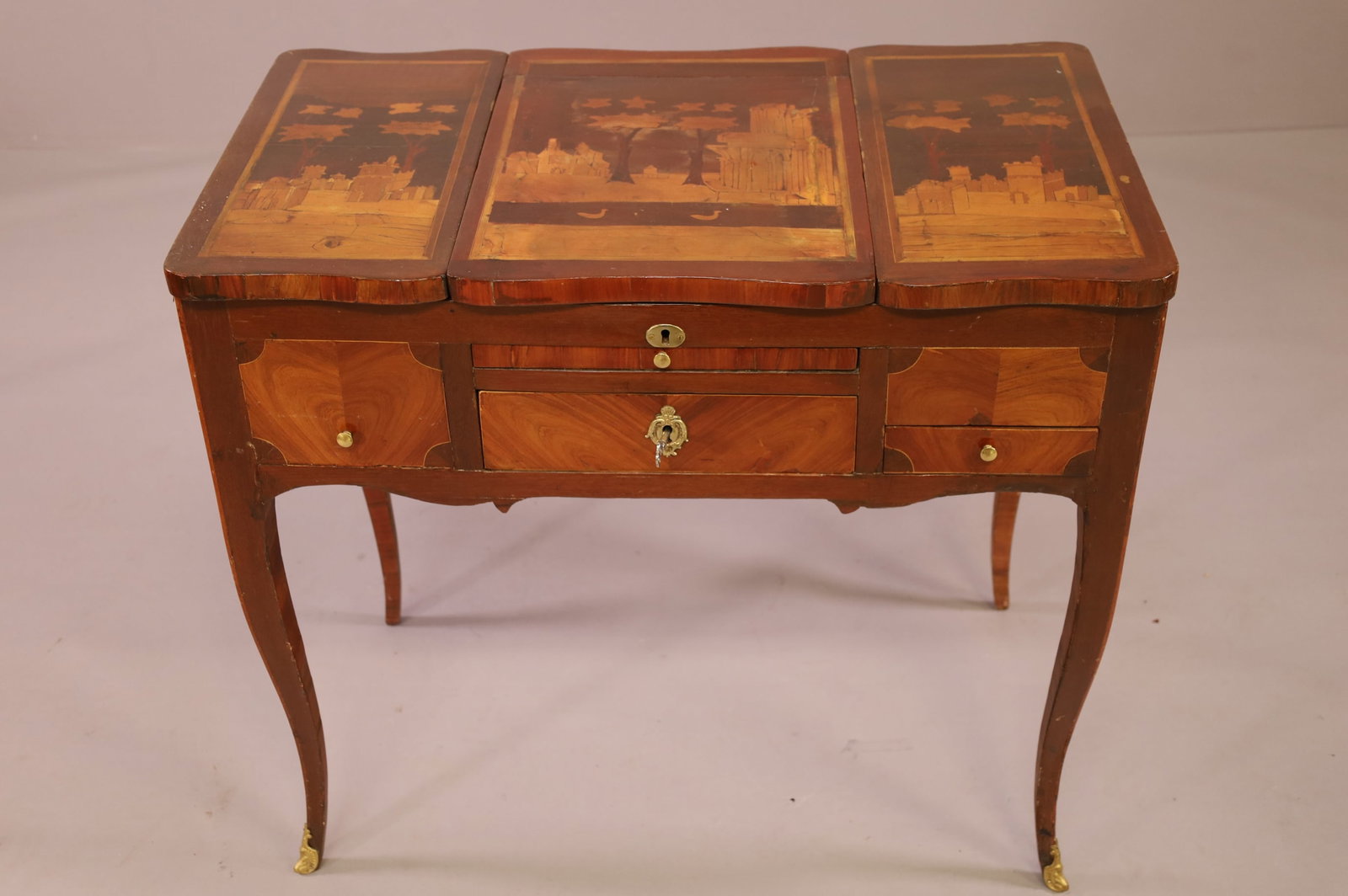 19TH CENTURY MARQUETRY INLAID VANITY: 19TH CENTURY INLAID VANITY, CASTLE SCENE INLAY. FLIP TOP WITH FITTED INTERIOR AND SOMPARTMENTS. WITH KEY. VENEER DAMAGE. 31" W x 18 1/2" D x 28" H. THIS ITEM EXCEEDS SIZE LIMITATIONS FOR IN HOUSE SHIP