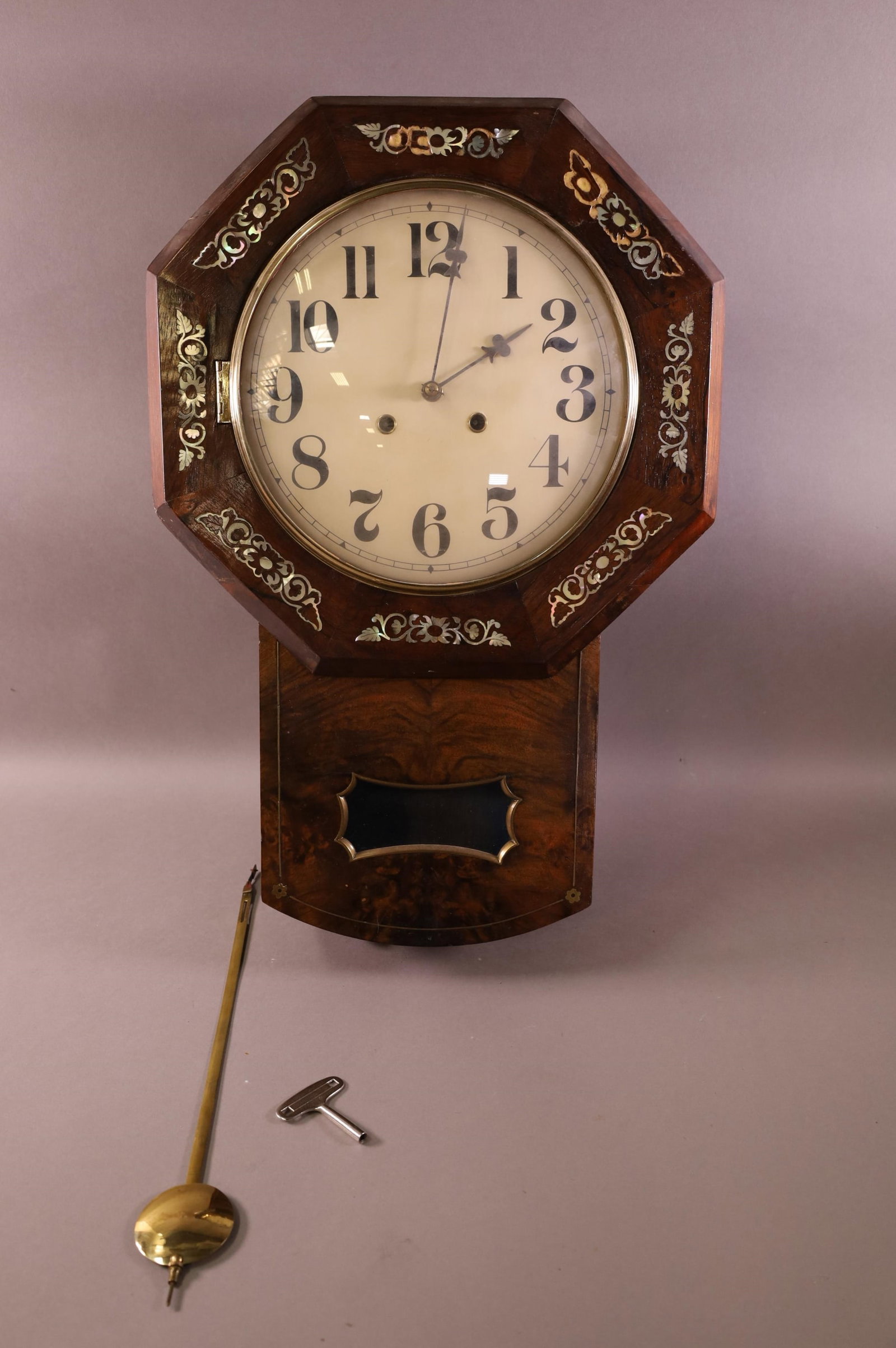 ANTIQUE INLAID WALL CLOCK: S. KAMERER. MOTHER OF PEARL INLAY (SOME IS MISSING). HAS KEY AND PENDULUM. 21" TALL. ALL CLOCKS ARE SOLD ASIS WITH NO GUARANTEE OF WORKING ORDER.