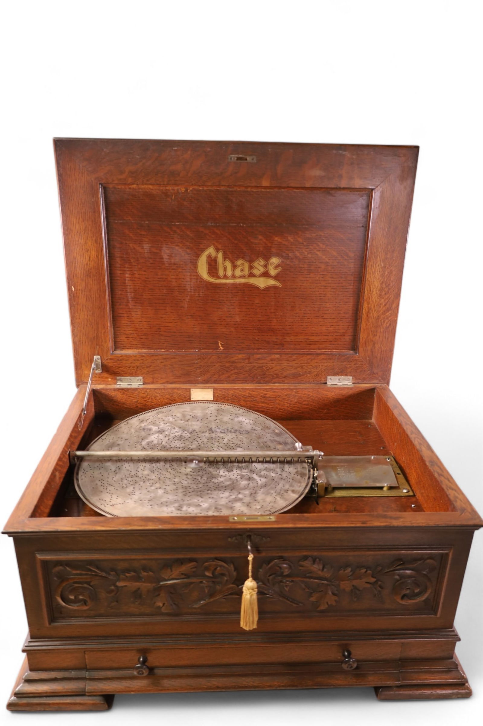 HIGHLY CARVED OAK CHASE DISK MUSIC BOX: ANTIQUE CHASE MUSIC BOX, IN LARGE OAK CASE, WITH CRANK. LOWER DRAWER. 6 DISCS. WORKING CONDITION. MINOR WEAR TO FINISH ON CASE, HAS A FEW TEETH MISSING. 29 1/2" W x 22" D x 14" H. 17" DISCS. THIS ITEM