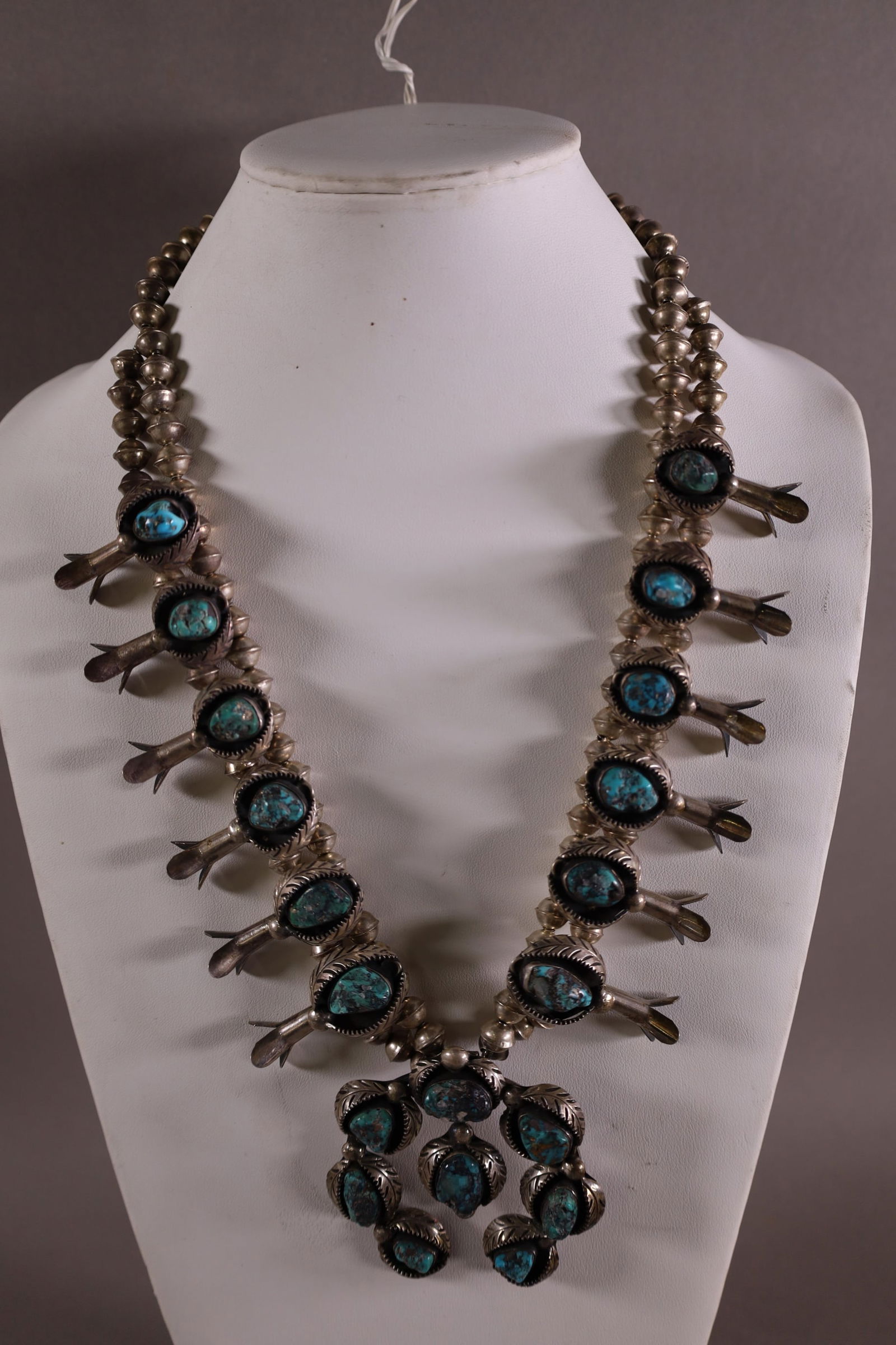 STERLING SILVER & TURQUOISE SQUASH BLOSSOM: HANDMADE NATIVE AMERICAN NAVAJO STERLING SILVER & TURQUOISE SQUASH BLOSSOM NECKLACE. UNMARKED, UNSIGNED. 15" L APPROX 252 GRAMS TOTAL WEIGHT.