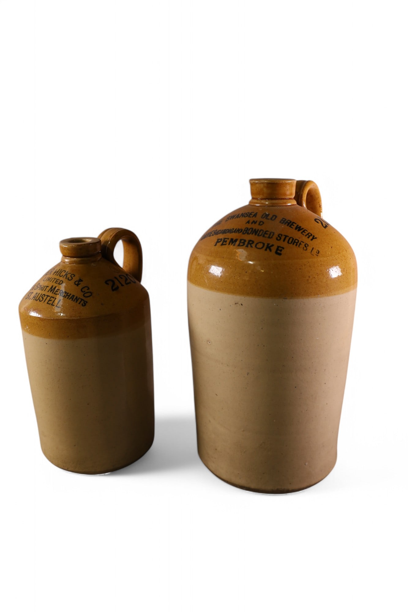 2 CROCK JUGS: 2 STONEWARE CROCK JUGS, LIQUOR ADVERTISING JUGS. SWANSEA BREWERY & WALTER HICKS WINE AND SPIRIT. SMALL CHIP TO RIM. 13" & 16" H.