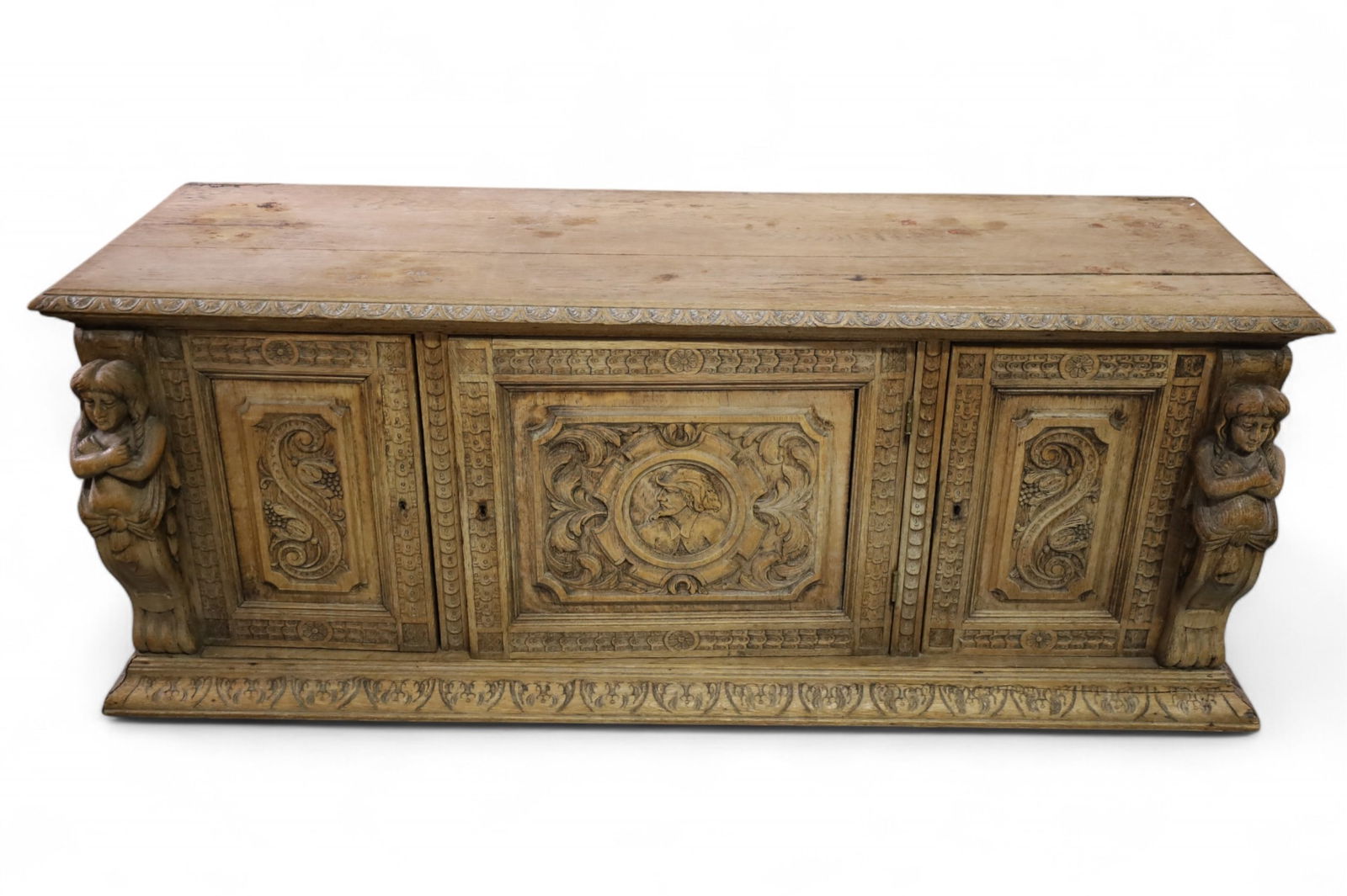 FIGURAL CARVED CHEST: UNFINISHED OAK, FIGURAL CARVED CHEST, THREE LOWER DOORS. AGE SPLITS. 60" W x 19" D x 24" H. THIS ITEM EXCEEDS SIZE LIMITATIONS FOR IN HOUSE SHIPPING, MUST BE PICKED UP IN HOUSE OR SHIPPED VIA 3rd PART
