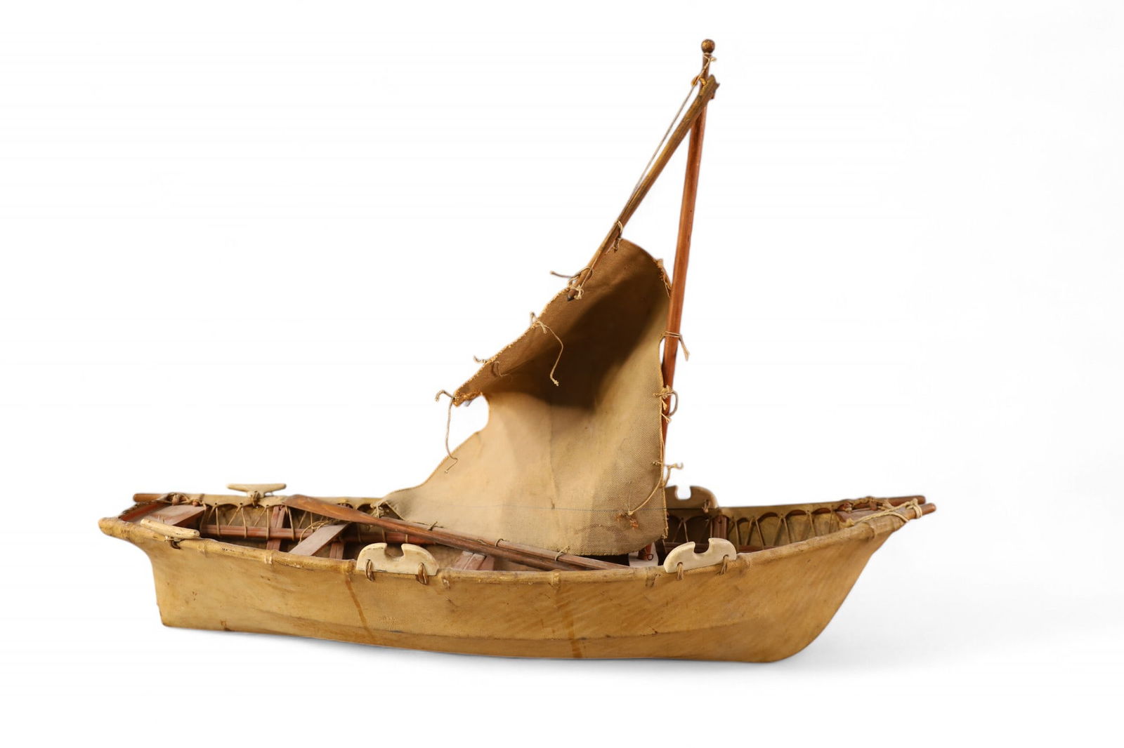 ESKIMO BOAT: LEATHER WRAPPED ESKIMO BOAT, WITH BONE DECORATION. MISSING OAR. 28" L. THIS ITEM EXCEEDS SIZE LIMITATIONS FOR IN HOUSE SHIPPING, MUST BE PICKED UP IN HOUSE OR SHIPPED VIA 3rd PARTY GROUND SHIPPER.