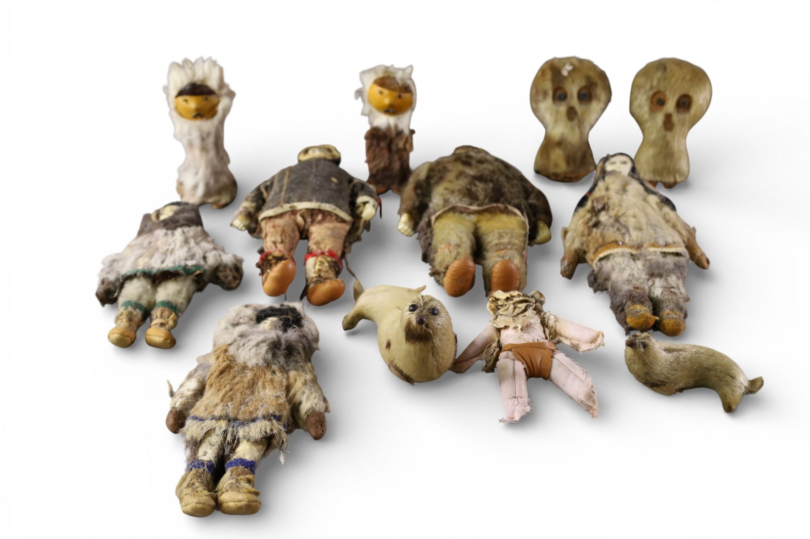 COLLECTION OF ALASKA INUIT DOLLS: 12 ALASKAN INUIT DOLLS WITH FUR DECORATION, BONE CARVED FACES, DAMAGE TO CLOTHING. 6" - 10" H.
