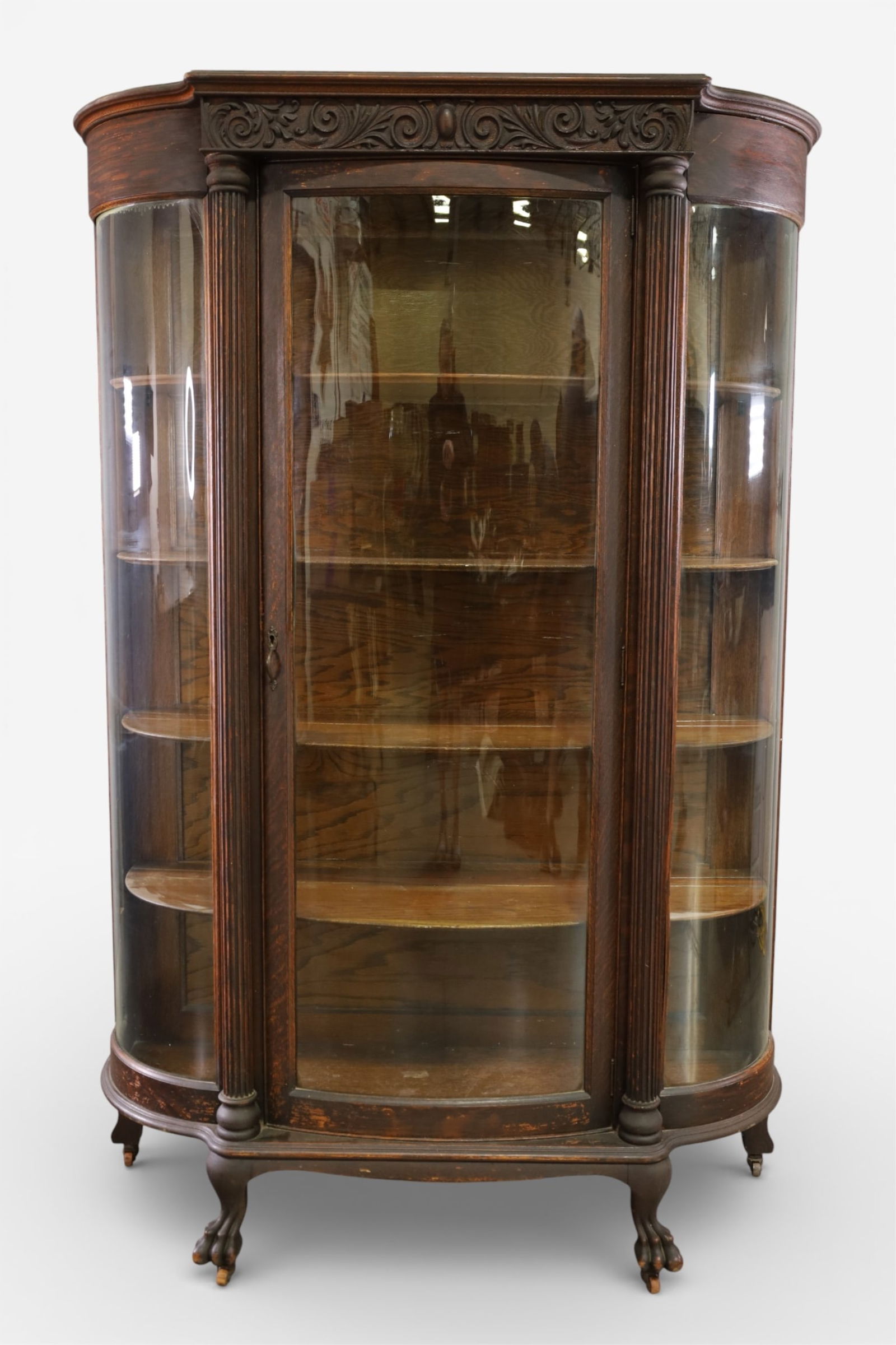 1900'S AM. OAK CHINA CABINET: OAK SINGLE DOOR CHINA CABINET, CURVED GLASS INTERIOR WOOD SHELVES. CLAW FEET WEAR TO FINISH. 46" W x 17" D x 69" H. THIS ITEM EXCEEDS SIZE LIMITATIONS FOR IN HOUSE SHIPPING, IT MUST BE PICKED UP IN HO