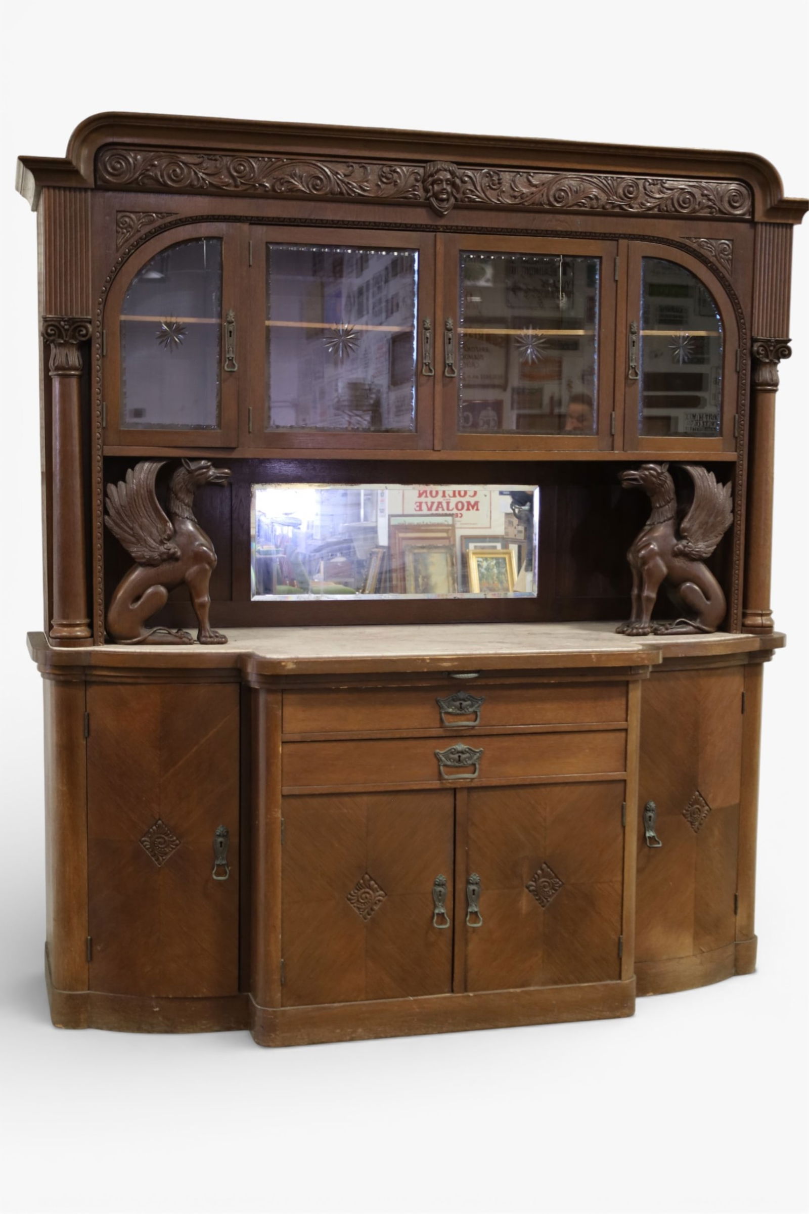 WINGED GRIFFIN MARBLE TOP SIDEBOARD: WING GRIFFIN CARVED WITH ETCHED BEVELED UPPER DOORS, MARBLE TOP SIDEBOARD. 77" W x 27" D x 86" H. THIS ITEM EXCEEDS SIZE LIMITATIONS FOR IN HOUSE SHIPPING, MUST BE PICKED UP IN HOUSE OR SHIPPED 
