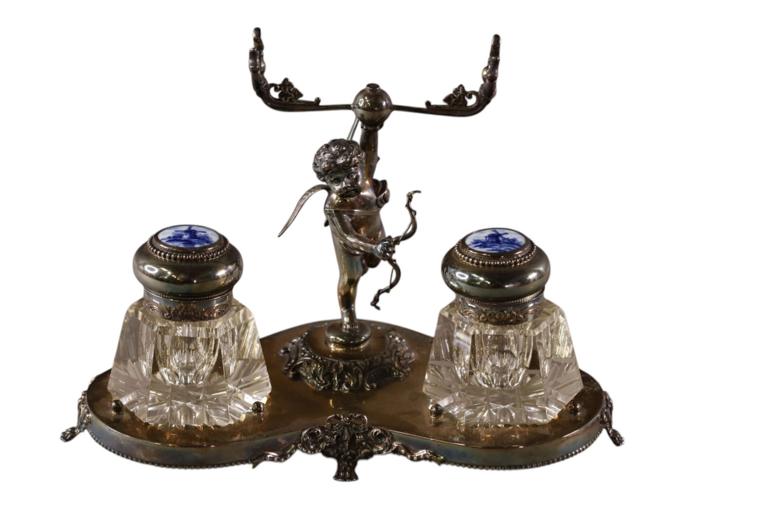 SILVERPLATED CHERUB INKWELL: VICTORIAN SILVERPLATED DERBY INKWELL WITH DELFT INKWELL TOPS. 9 1/2" W.