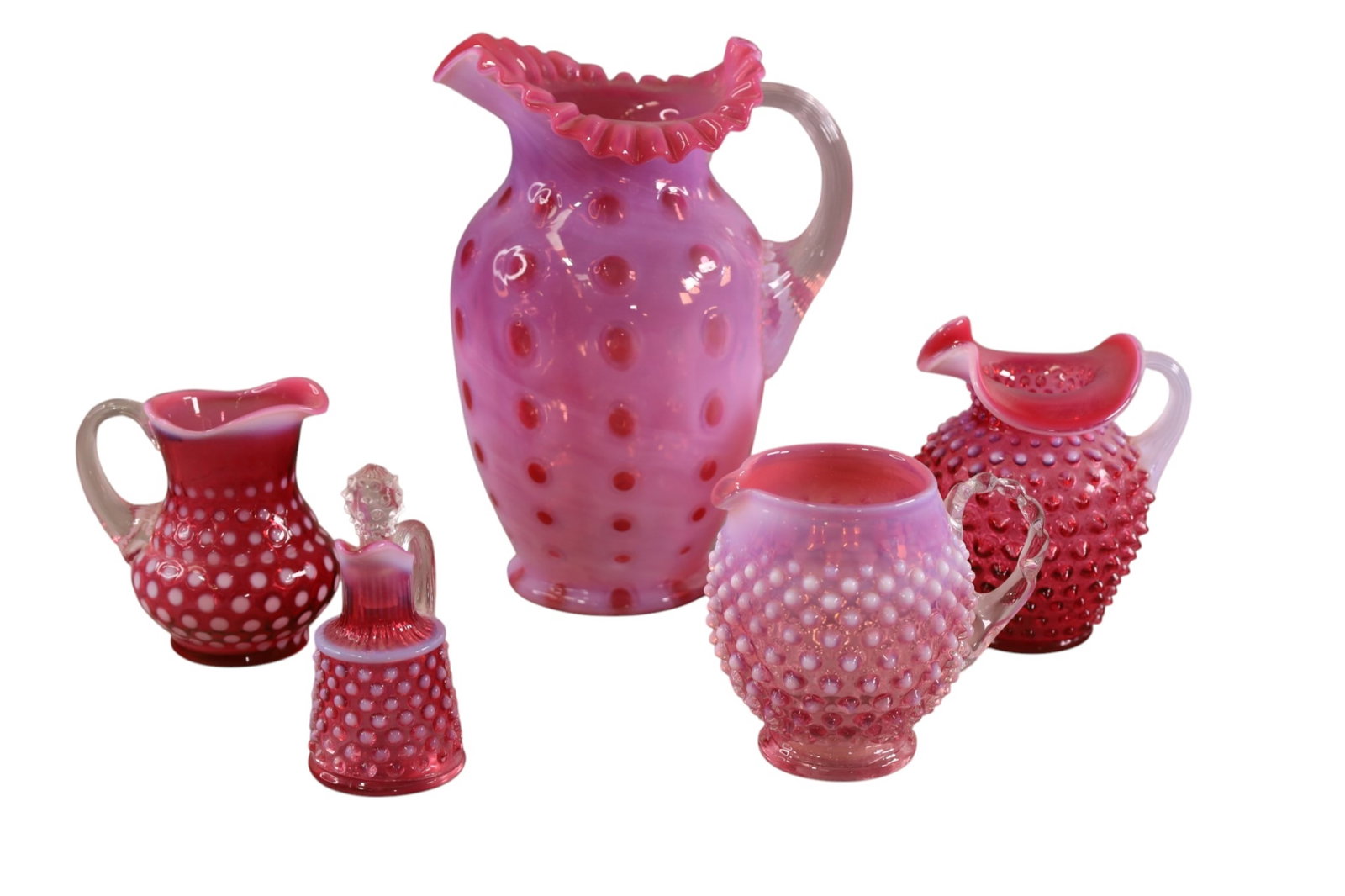 5 PIECES OF FENTON GLASS: 4 CRANBERRY GLASS HOBNAIL PITCHERS AND CRUET. 4 TO 10"H