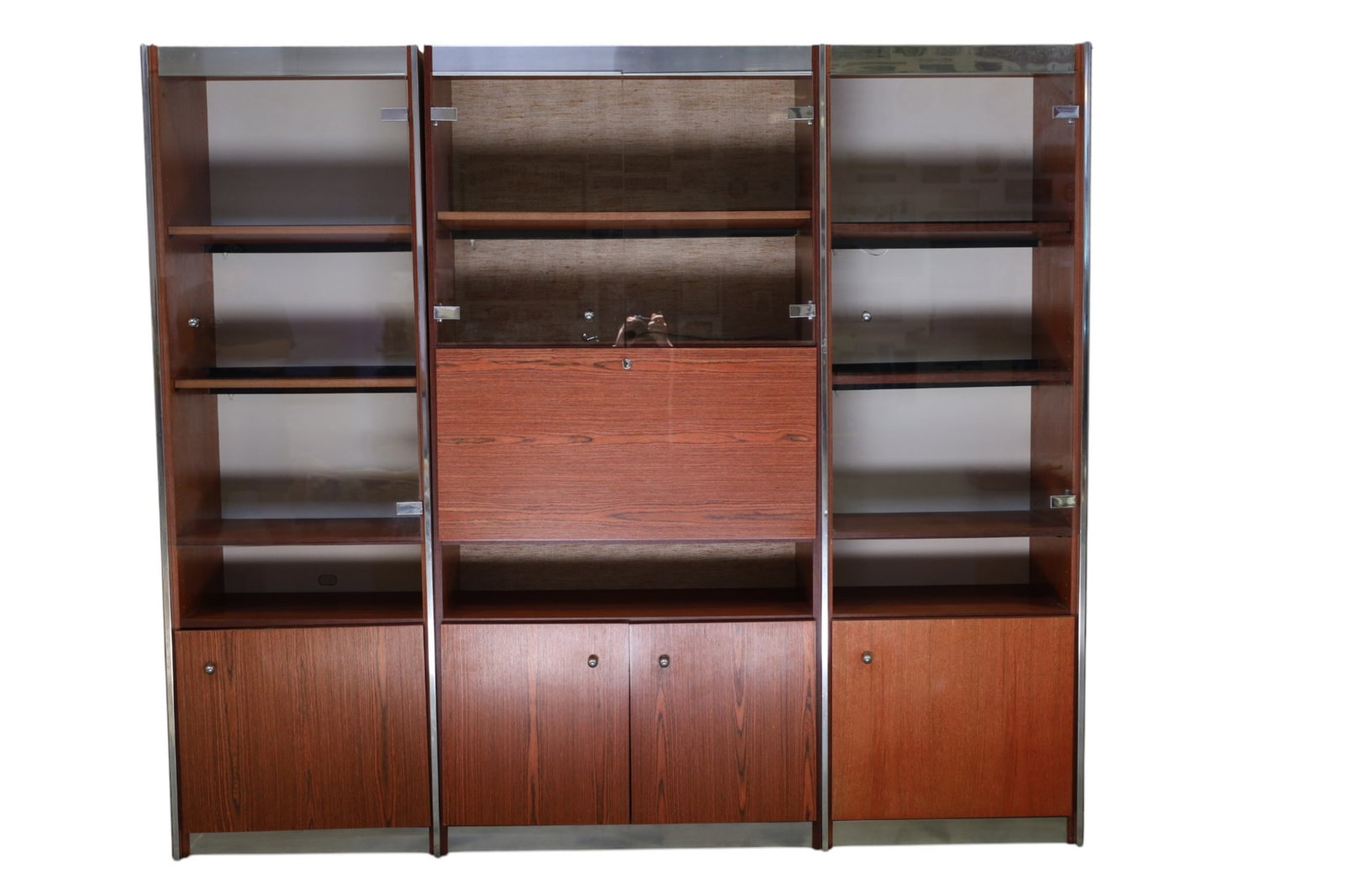 3 PIECE MCM WALL UNIT: 3 PART MID CENTURY MODERN WALL UNIT, FREESTANDING WALL UNIT, TEAK AND CHROME, WITH GLASS DOORS. DROP FRONT DESK IN CENTER UNIT. ONE HANDLE IS BROKEN, 85" W x 16" D x 74 1/2" H. THIS ITEM EXCEEDS