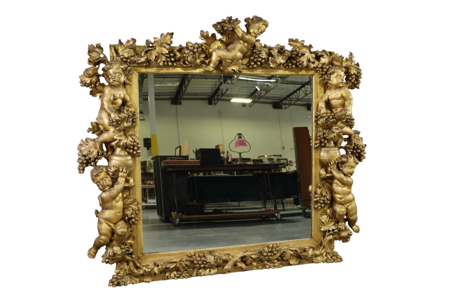 LARGE ORNATE GOLD GILT WALL MIRROR: LARGE GOLD GILT GESSO AND WOOD ORNATE WALL MIRROR WITH PUTTI AND GRAPE MOTIF, REPAIRS AND BREAKS THROUGHOUT. 70" x 61" THIS ITEM EXCEEDS SIZE, WEIGHT, AND OR FRAGILITY LIMITATIONS FOR IN HOUSE