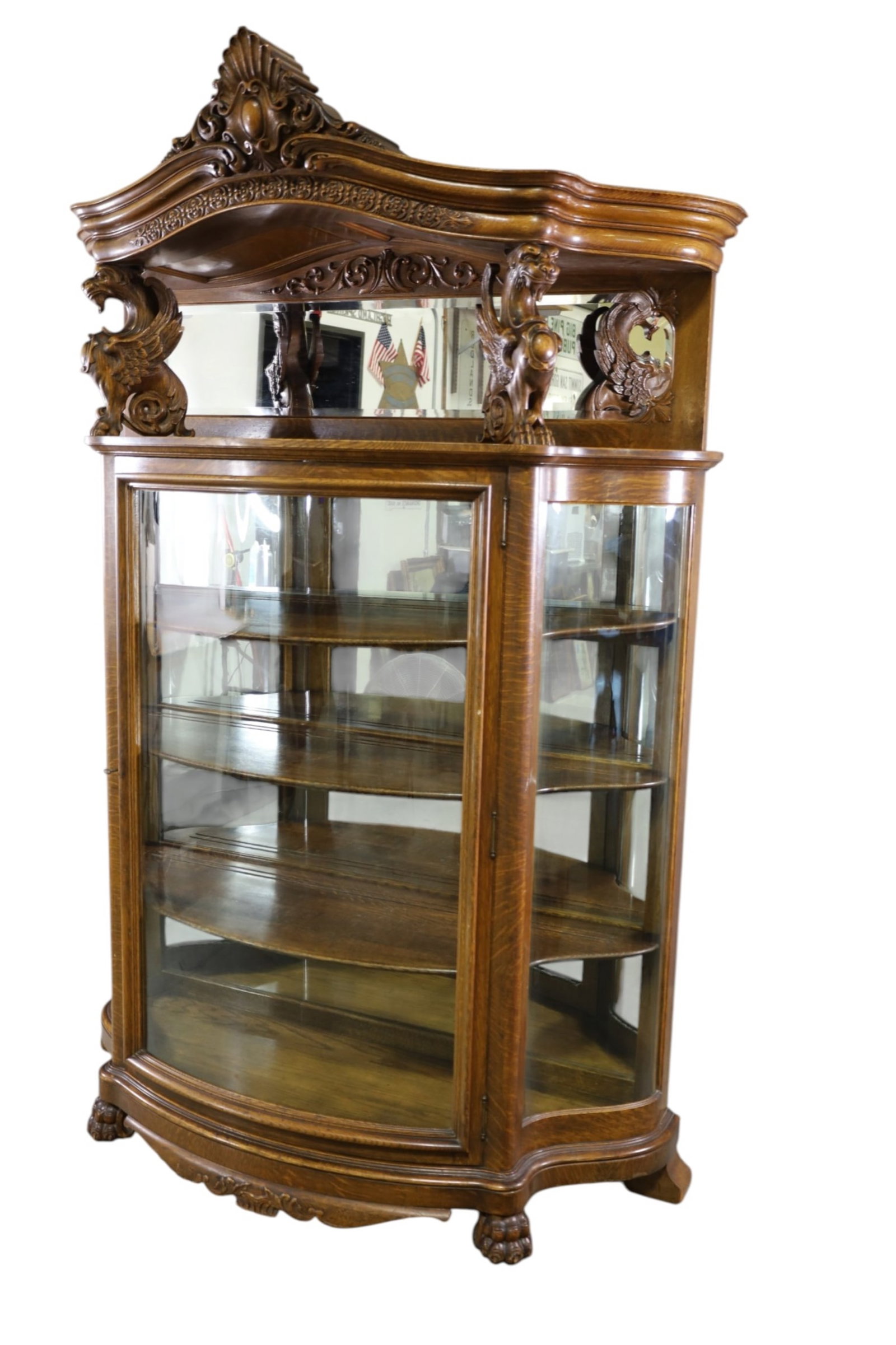 RJ HORNER CHINA CABINET: LARGE AMERICAN OAK, WINGED GRIFFIN SERPANTINE GLASS CHINA CABINET BY RJ HORNER, LARGE CLAW FOOT, MIRRORED BACK, INTERIOR WOODEN SHELVES. 55" W x 19 1/2" D x 85" H. THIS ITEM EXCEEDS SIZE, WEIGHT,