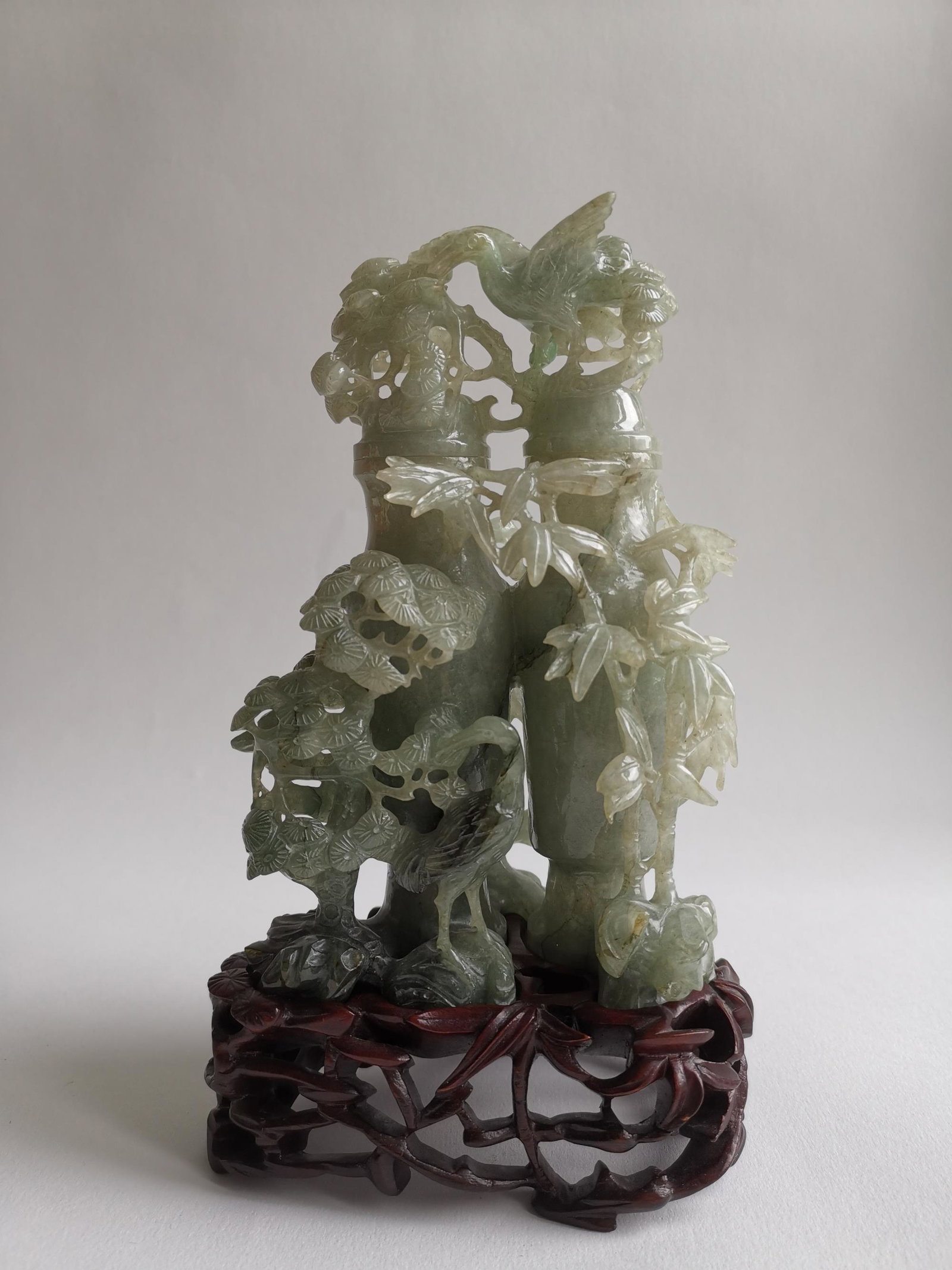 19/20th C. CHINESE CARVED PINE BAMBOO PLUM JADEITE: LATE 19TH C./ ERALY 20th C. CHINESE CARVING PINE, BAMBOO AND PLUM JADEITE BOTTLE, WITH ORIGINAL RED WOOD STAND AND CARVED PINE, BANBOO AND PLUM TOO. H (WITH WOOD STAND) 7 1/4 INCHES.